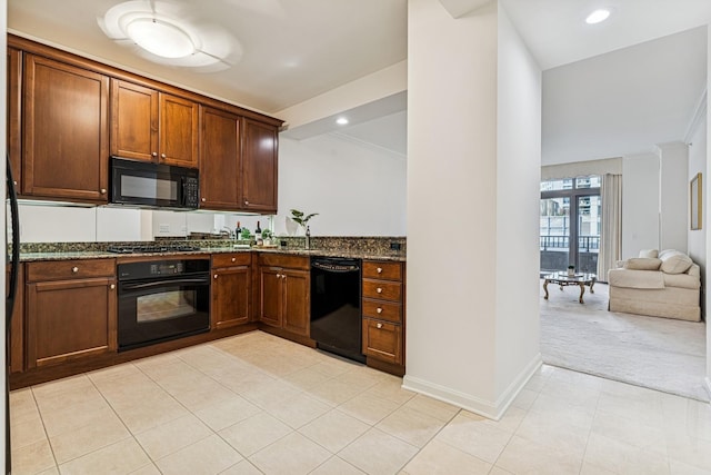 kitchen featuring baseboards, light colored carpet, dark stone countertops, light tile patterned flooring, and black appliances