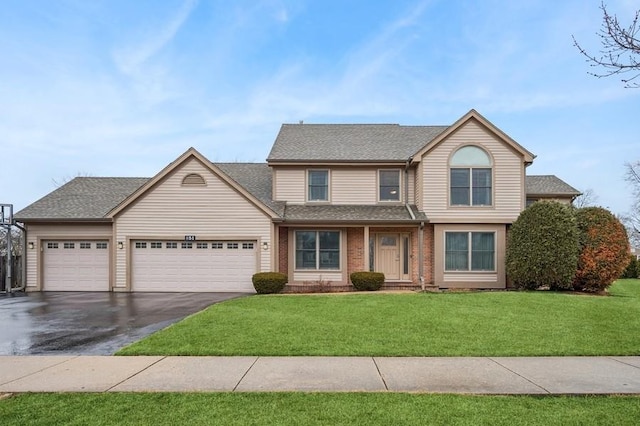 traditional-style home with aphalt driveway, brick siding, a shingled roof, an attached garage, and a front lawn