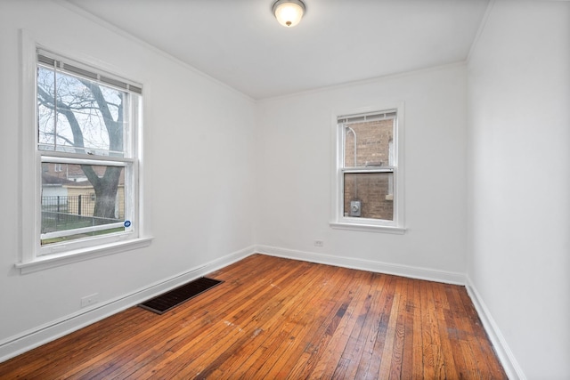 empty room featuring baseboards, crown molding, visible vents, and hardwood / wood-style floors