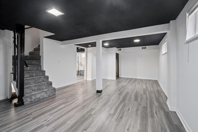 finished basement featuring stairway, wood finished floors, visible vents, and baseboards