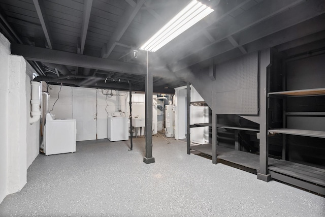 unfinished basement with water heater, a sink, and washing machine and dryer