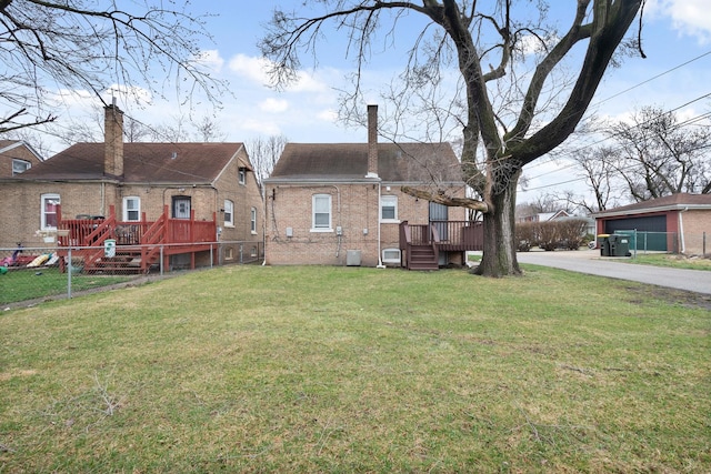 rear view of property featuring a yard, fence, a deck, and brick siding