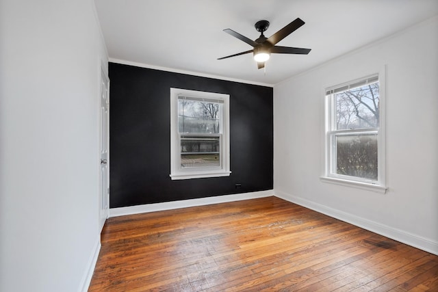 empty room featuring a ceiling fan, baseboards, crown molding, and hardwood / wood-style floors