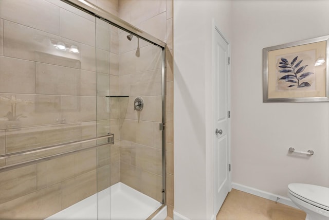 bathroom featuring a stall shower, tile patterned flooring, toilet, and baseboards