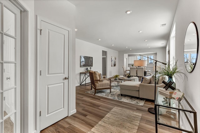 living room with recessed lighting, visible vents, and wood finished floors