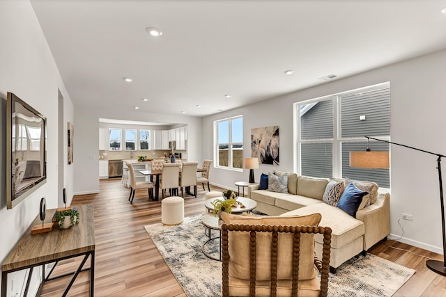 living room featuring baseboards, light wood-type flooring, and recessed lighting