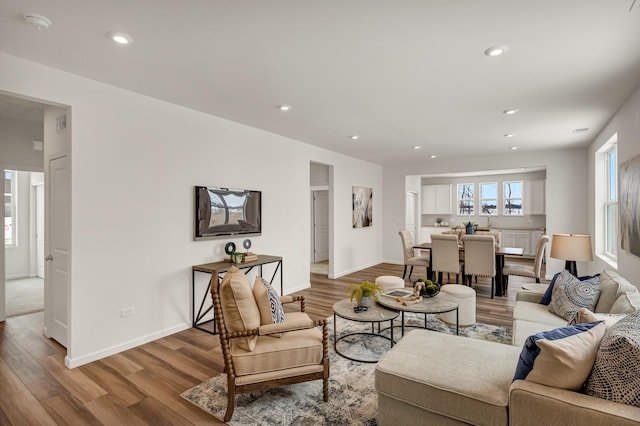 living room with recessed lighting, visible vents, baseboards, and wood finished floors