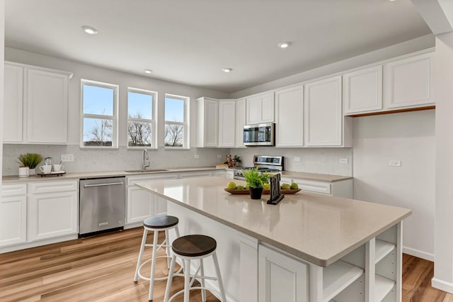 kitchen featuring stainless steel appliances, white cabinets, a sink, and open shelves