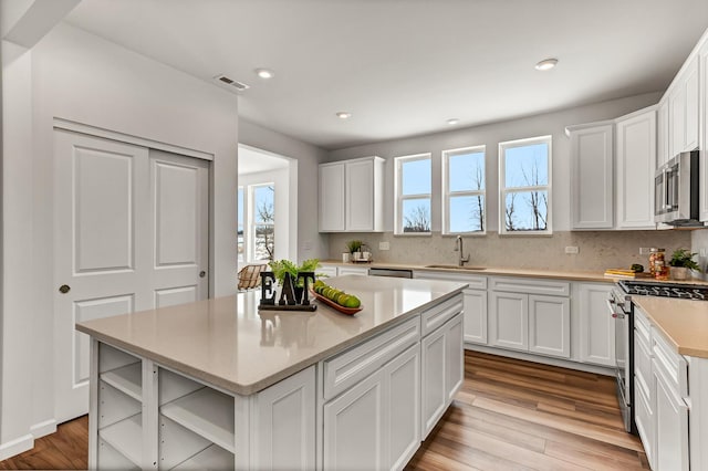 kitchen with a sink, visible vents, white cabinetry, appliances with stainless steel finishes, and open shelves