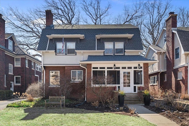 view of front of property with stucco siding, brick siding, roof with shingles, and a chimney