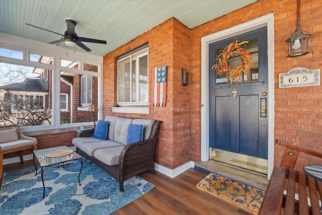 property entrance with outdoor lounge area, a porch, a ceiling fan, and brick siding