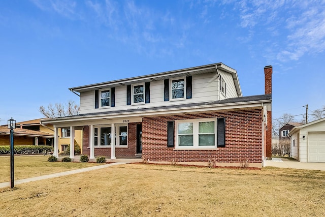 traditional-style home featuring covered porch, an outdoor structure, a garage, brick siding, and a chimney