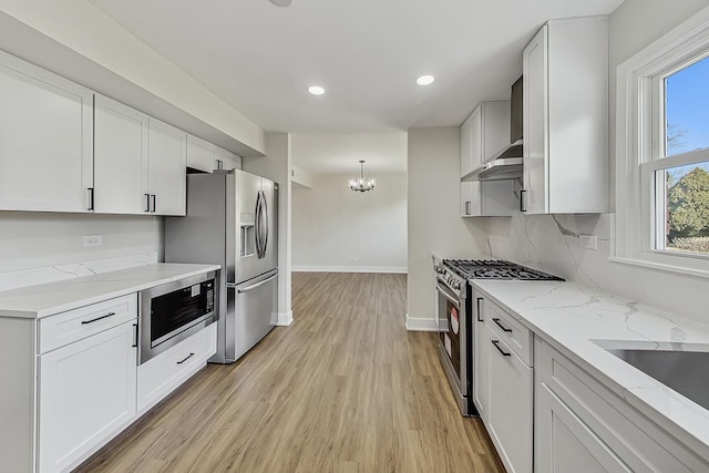 kitchen with light stone counters, white cabinetry, stainless steel appliances, light wood finished floors, and baseboards