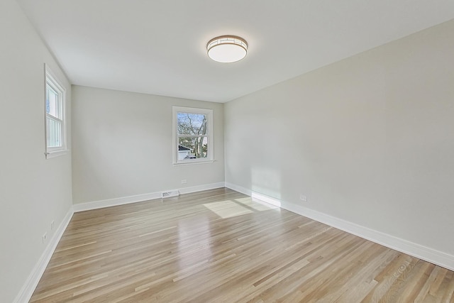 spare room featuring visible vents, baseboards, and light wood finished floors