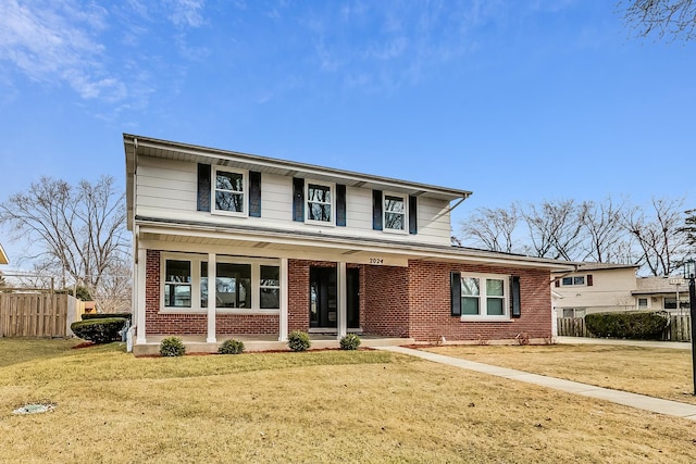 traditional home featuring a front yard, a porch, fence, and brick siding