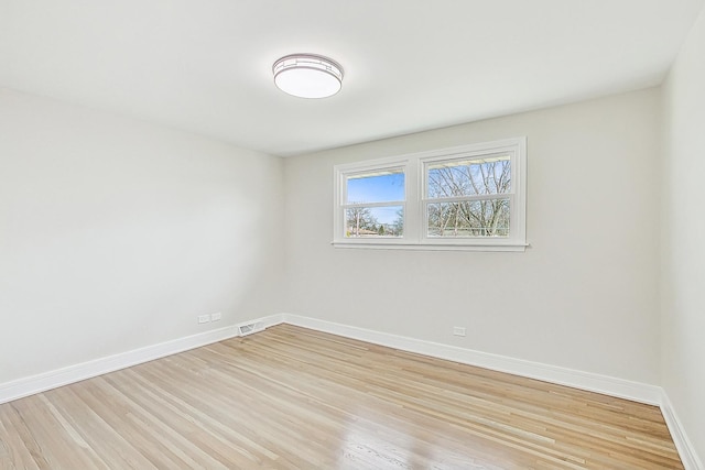 spare room featuring visible vents, baseboards, and light wood-style floors