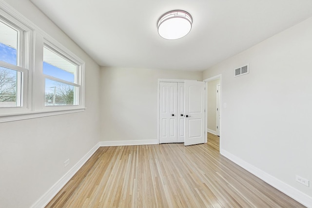 empty room featuring visible vents, baseboards, and light wood-style flooring