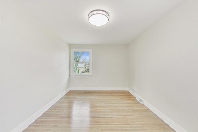 empty room with light wood-type flooring, visible vents, and baseboards