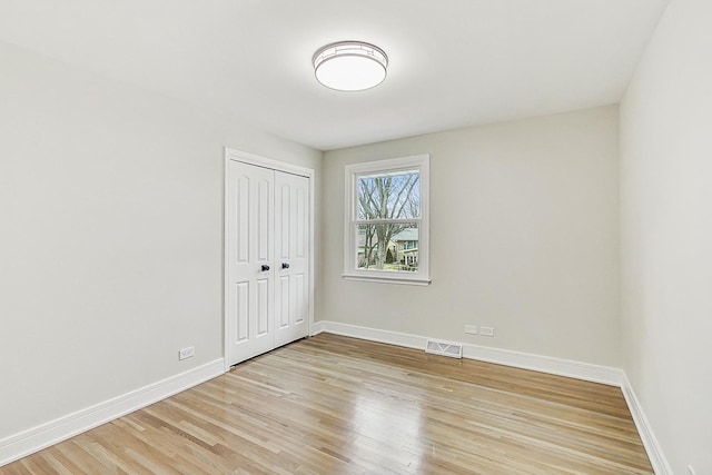 unfurnished bedroom with visible vents, baseboards, a closet, and light wood-style flooring