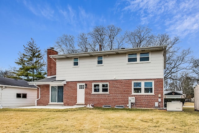 rear view of property featuring a yard, brick siding, a chimney, and a patio area