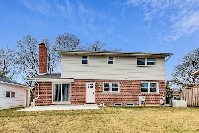 back of property with brick siding, a patio area, a chimney, and a yard