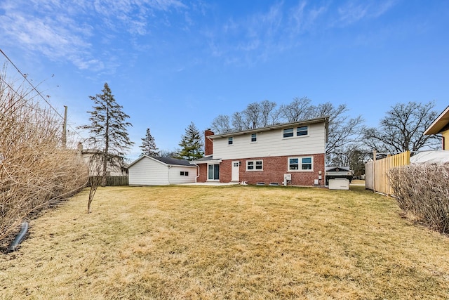 rear view of house with brick siding, a chimney, a lawn, and fence