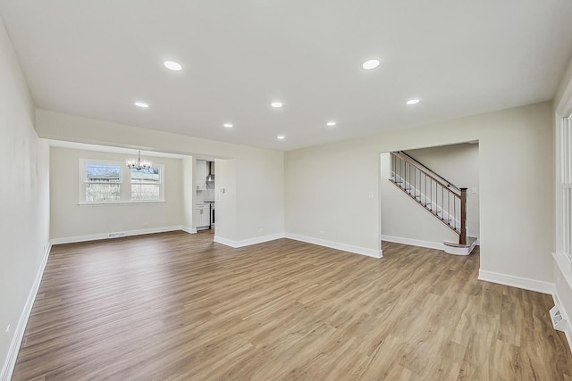 unfurnished living room featuring light wood finished floors, baseboards, stairs, recessed lighting, and a notable chandelier