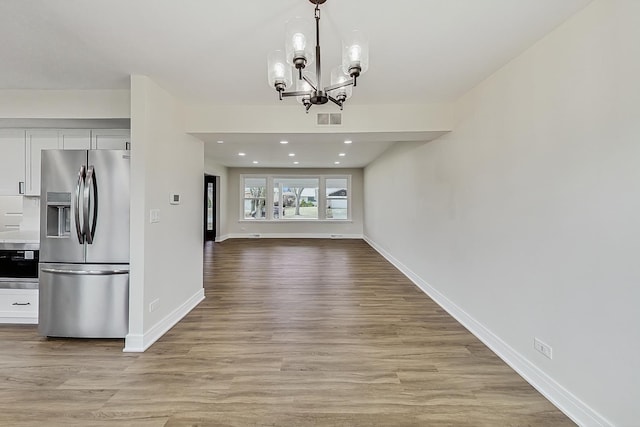 interior space with visible vents, an inviting chandelier, white cabinets, light wood-style floors, and stainless steel refrigerator with ice dispenser