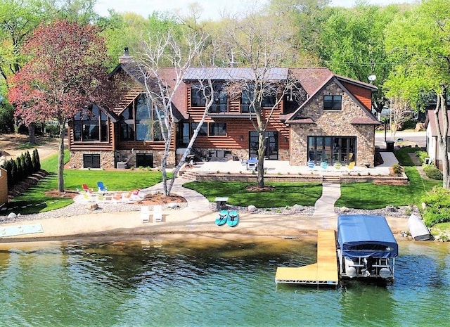 back of property with stone siding, a water view, stairs, a yard, and a patio area