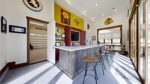 bar with baseboards, a towering ceiling, and recessed lighting