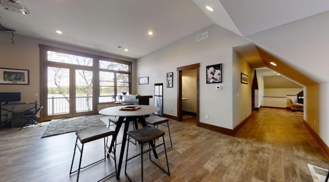 dining area featuring vaulted ceiling, wood finished floors, visible vents, and baseboards