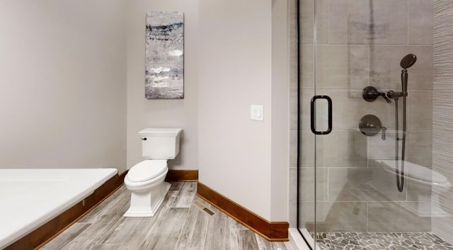 full bath featuring toilet, a shower stall, baseboards, and wood finished floors