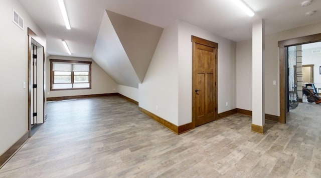 additional living space with lofted ceiling, light wood-type flooring, visible vents, and baseboards