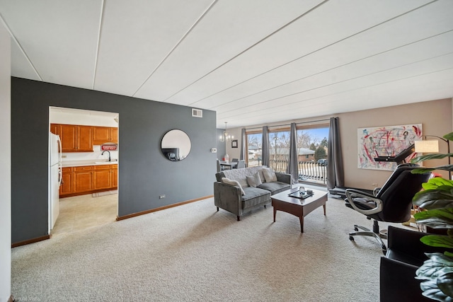 living room with visible vents, baseboards, a chandelier, and light colored carpet