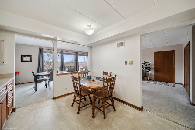 dining area with baseboards, visible vents, and light colored carpet