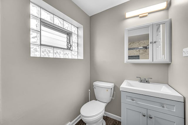 bathroom featuring toilet, vanity, baseboards, and wood finished floors