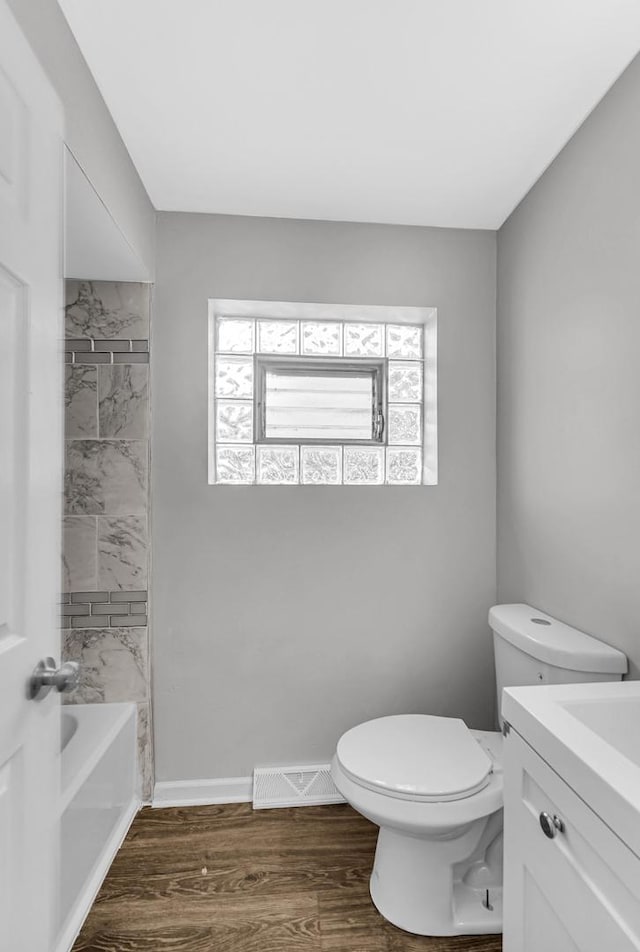 bathroom with visible vents, toilet, vanity, wood finished floors, and baseboards