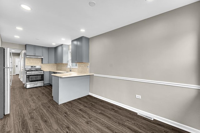 kitchen featuring visible vents, a peninsula, gray cabinets, stainless steel appliances, and a sink