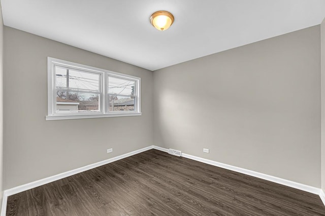 unfurnished room featuring baseboards, visible vents, and dark wood-style flooring