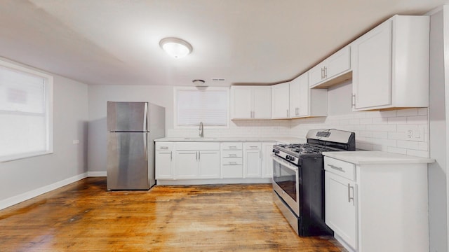 kitchen with light wood-type flooring, tasteful backsplash, stainless steel appliances, and a sink