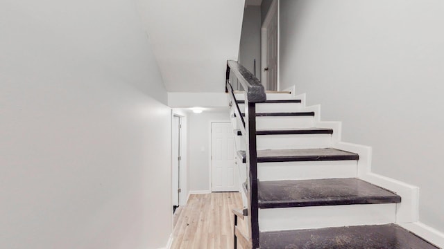 staircase featuring wood finished floors and baseboards