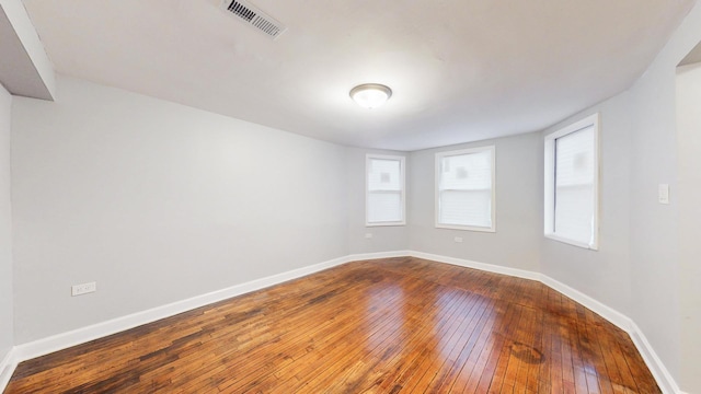 unfurnished room featuring baseboards, visible vents, and dark wood-type flooring