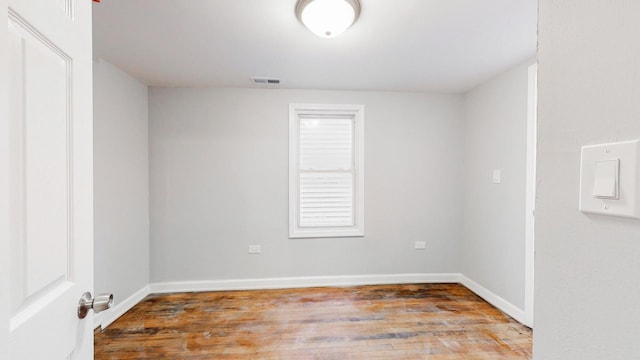 spare room with wood finished floors, baseboards, and visible vents