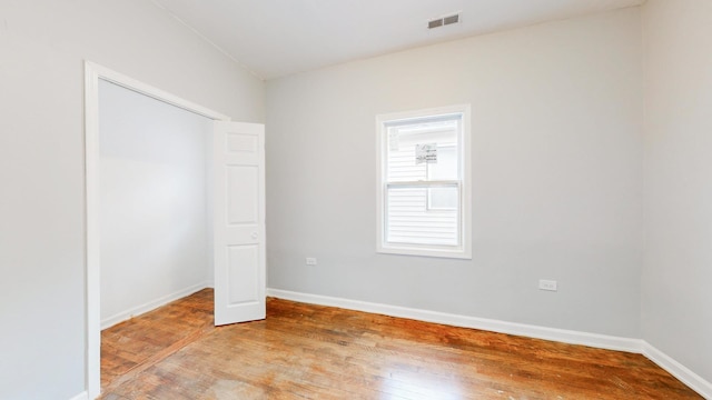 unfurnished bedroom featuring a closet, hardwood / wood-style flooring, baseboards, and visible vents