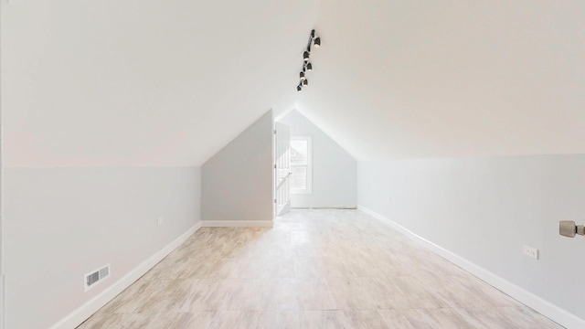 additional living space with baseboards, vaulted ceiling, and visible vents
