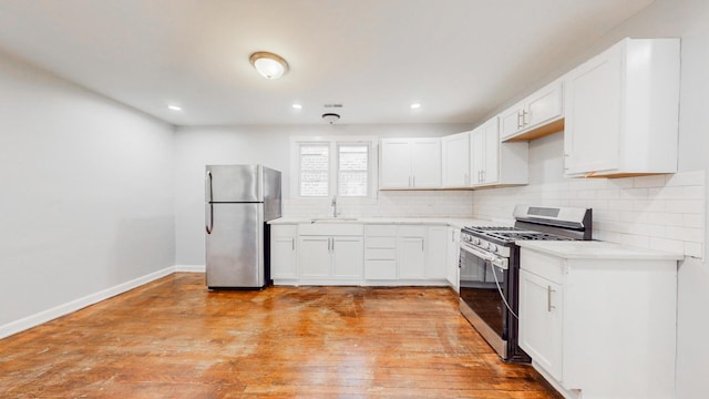 kitchen with baseboards, white cabinets, appliances with stainless steel finishes, decorative backsplash, and light wood finished floors