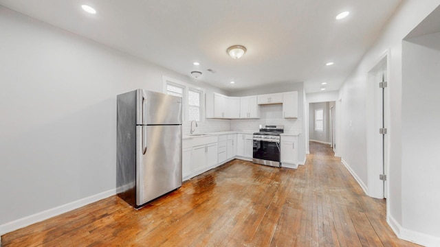 kitchen with white cabinetry, light countertops, appliances with stainless steel finishes, tasteful backsplash, and wood-type flooring