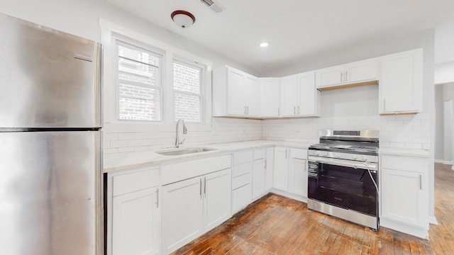 kitchen with visible vents, light wood-style flooring, stainless steel appliances, light countertops, and a sink