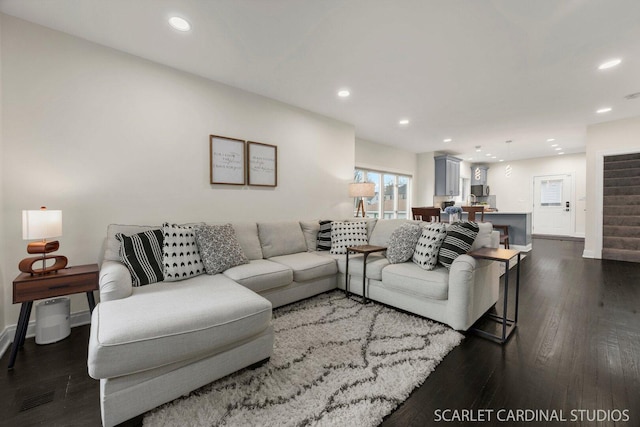 living area with recessed lighting, dark wood-style flooring, baseboards, and stairs