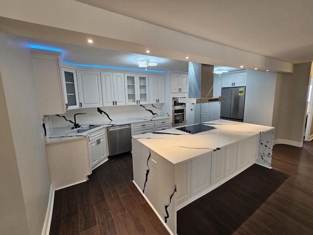 kitchen with a center island, dark wood-style flooring, stainless steel appliances, white cabinets, and wall chimney range hood